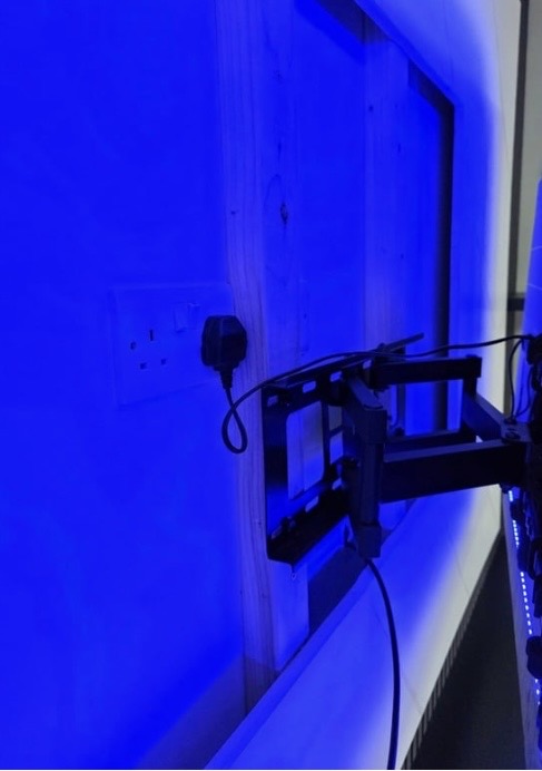 Behind-the-TV detail showing concealed cabling, double socket and full-motion double-arm bracket on the marble back panel